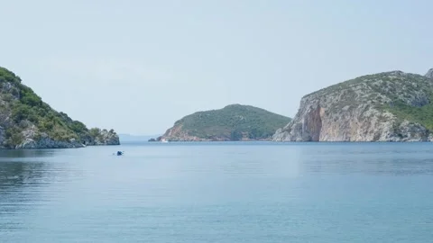 Single kayak floating on the tranquil waters of Porto Koufo, surrounded by rocky Stock Footage 346705493