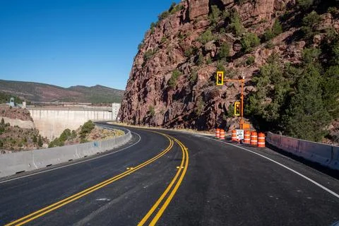 Single-lane construction temporary stoplight controls traffic at a dam while Stock Photos