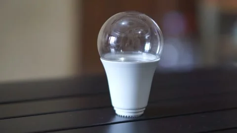 Single LED light bulb on a table indoors, representing bright ideas, creativity Stock Footage 323792068