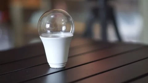 Single LED light bulb on a table indoors, representing bright ideas, creativity Stock Footage 323792072