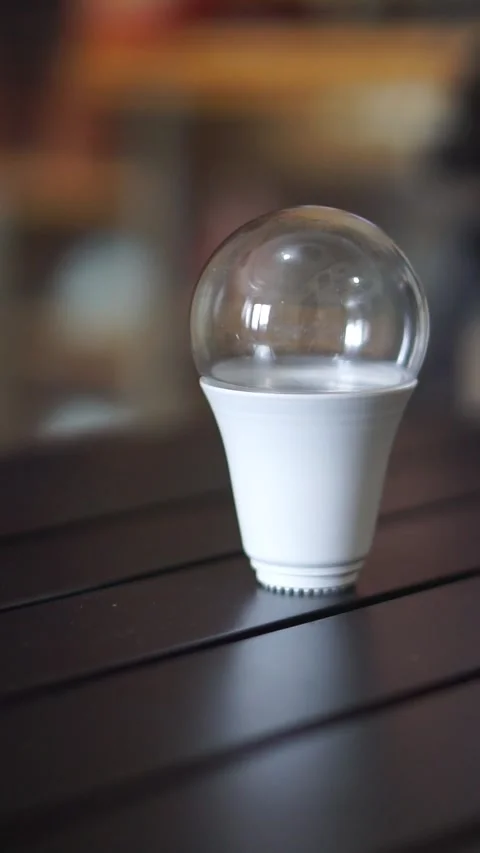 Single LED light bulb on a table indoors, representing bright ideas, creativity Stock Footage 323792126