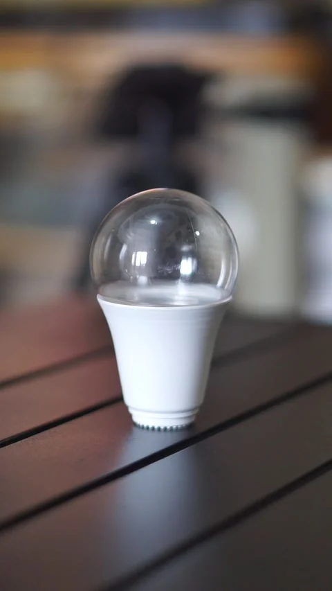 Single LED light bulb on a table indoors, representing bright ideas, creativity Stock Footage 323792161