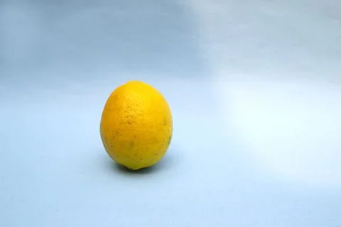 Single lemon fruit on blue background and light shadow Stock Photos