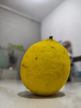 Single lemon rests on clean surface Stock Photos