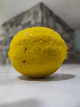 Single lemon rests on clean surface Stock Photos