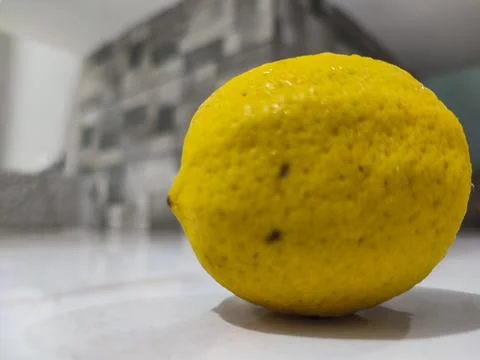 Single lemon rests on clean surface Stock Photos