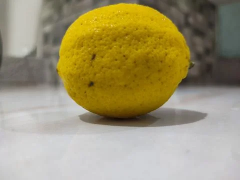 Single lemon rests on clean surface Stock Photos