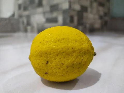 Single lemon rests on clean surface Stock Photos