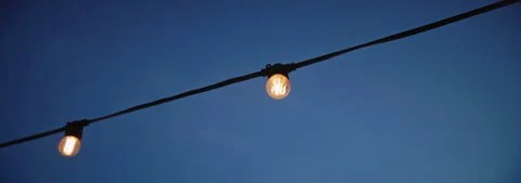 A Single Light Bulb Hanging Against a Beautiful Twilight Sky Brings Tranquility Stock Footage 314546310