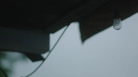 Single lightbulb hangs from the awning of a back patio on a dreary day Vídeos de archivo 251226503