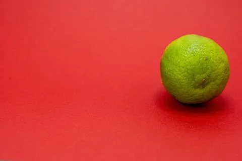 A single lime sits on a red background. Stock Photos