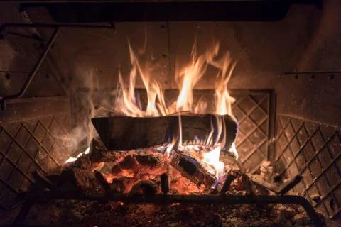 A single log on fire on top of coals 写真素材