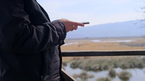 A single man on the bird watching tower and texting with his mobile phone Stock Footage 152958901