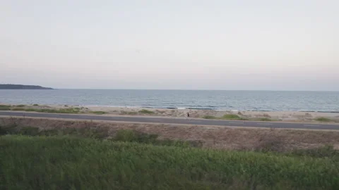 Single man cycling on the beach road early in the morning Stock Footage 159749320