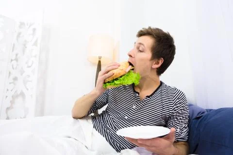 Single man eating in bed Stock Photos