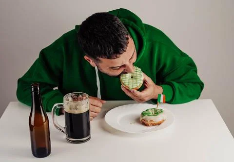 Single man having donuts and stout for breakfast to celebrate St. Patrick's Day Stock Photos