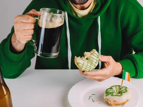 Single man having donuts and stout for breakfast to celebrate St. Patrick's Day Stock Photos
