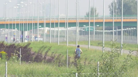 A single man jogging next to a motorway overpass Video stock 63765491