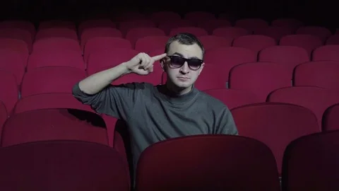 Single man sitting in comfortable red chairs in dark cinema theater and twists Stock Footage 83950345