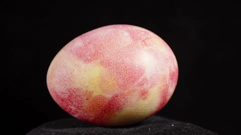A single marbled pink-yellow Easter egg is displayed against a black background, Video stock 295901166