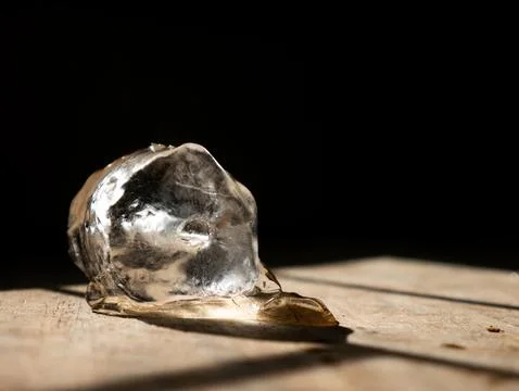 Single melting ice cube on rustic wooden table surface with dramatic sunlig.. Stock Photos