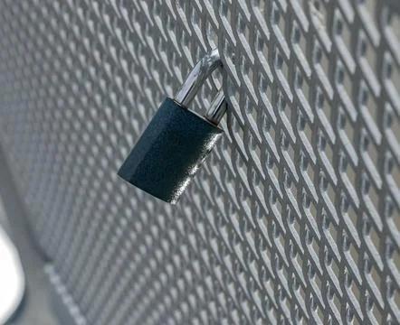 Single Metal Padlock Securing Textured Steel Grid Stock-Fotos