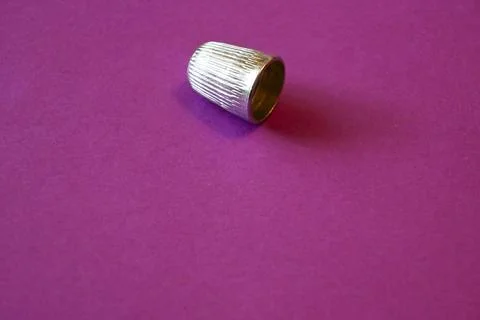 Single metal thimble on purple background, sewing and protection concept, Copy S Fotos Stock