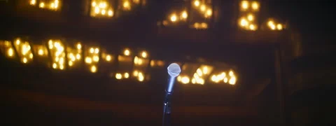 Single microphone on empty stage in large concert hall with ceiling glowing Stock Footage 250006763
