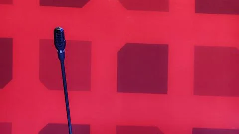 A single microphone mounted on a stand with red background. Stock Photos