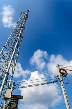 Single mobile tower and electricity post with blue sky. Stock Photos