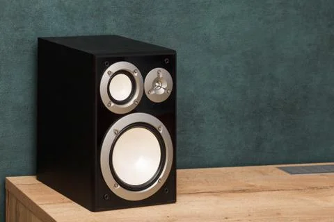 Single modern black audio speaker in interior on wooden desk near the wall Stock Photos