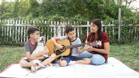 Single mom and sons play guitar together with fun  in the park Stockbeeldmateriaal 100751060