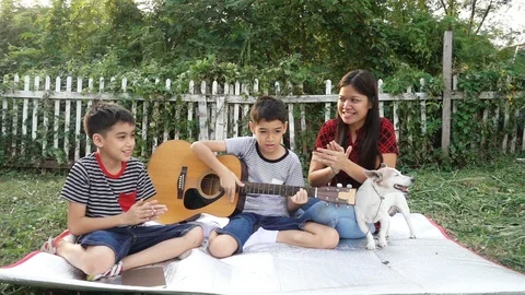 Single mom and sons play guitar together with fun  in the park Stock-Footage 100751151