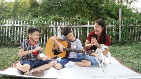 Single mom and sons play guitar together with fun  in the park Stockbeeldmateriaal 100751236