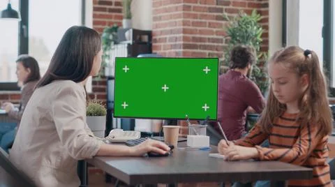 Single mom using computer with horizontal green screen, having little girl at Stock Photos