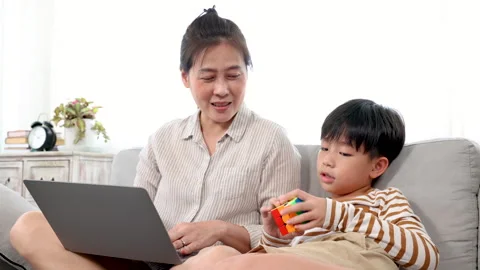 Single mom using laptop for work from home and son sitting next to mom tryi.. Stock Footage 249522545