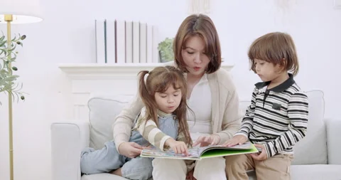 Single mother leans close behind kids, listens, nods, helps sister follow Stock Footage 341387116