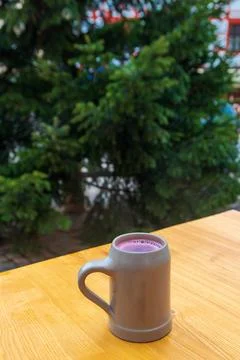 A single mug of hot mulled wine on a wooden table with green Christmas tree 스톡 사진