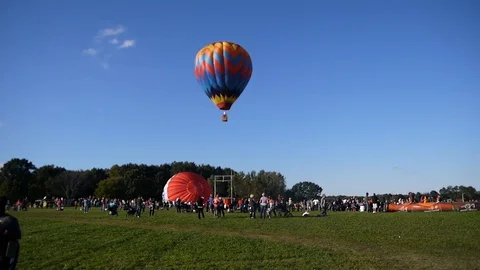 A single multi color bright hot air balloon is getting up in the air flying Stock Footage 95965859