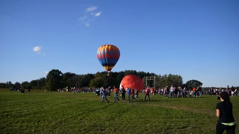 Single multi color bright hot air balloon is getting up in air people watching Stock Footage 95965869