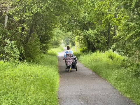 Single mum with pram walking alone on path in the countryside Stock Photos