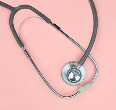 A single normal stethoscope isolated on top of a pink color paper background Stock Photos