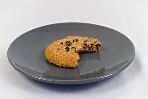 Single Oatmeal Cookie Missing a Bite on Gray Plate Foto stock