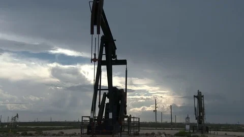 Single oil pump jack working against a dramatic sky, 4K. Stock Footage 79978936