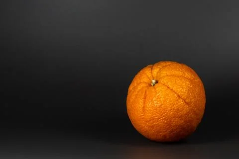 A single orange sits on a black background Stock Photos