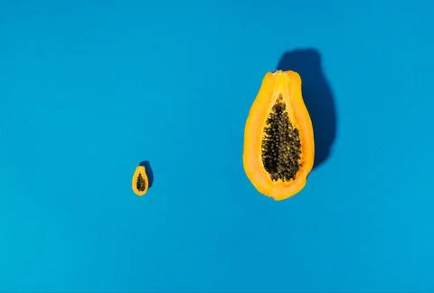 Single papaya fruit cutter on half on blue background Foto stock