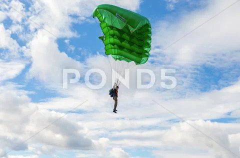 Single parachute jumper on a wing parachute on blue sky background Stock Photos