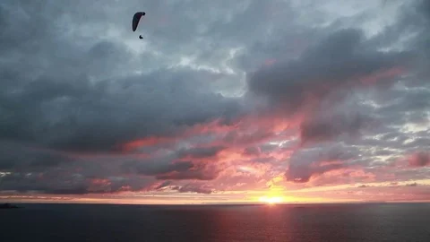 A single paraglider is joined by a second high above a pastel sky Stock Footage 82003146