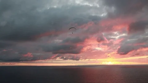 A single paraglider in the scene of a pastel sunset over the ocean Stock Footage 82003191