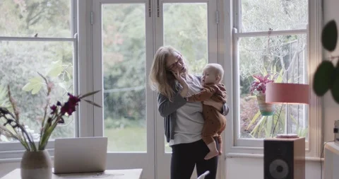 Single parent working from home on smart phone and holding baby Stock Footage 118620495
